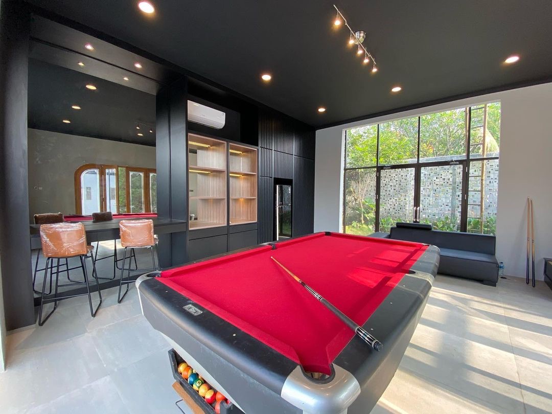 Ruang biliar dengan meja billiard, bar dan kabinet hijau tua bergaris